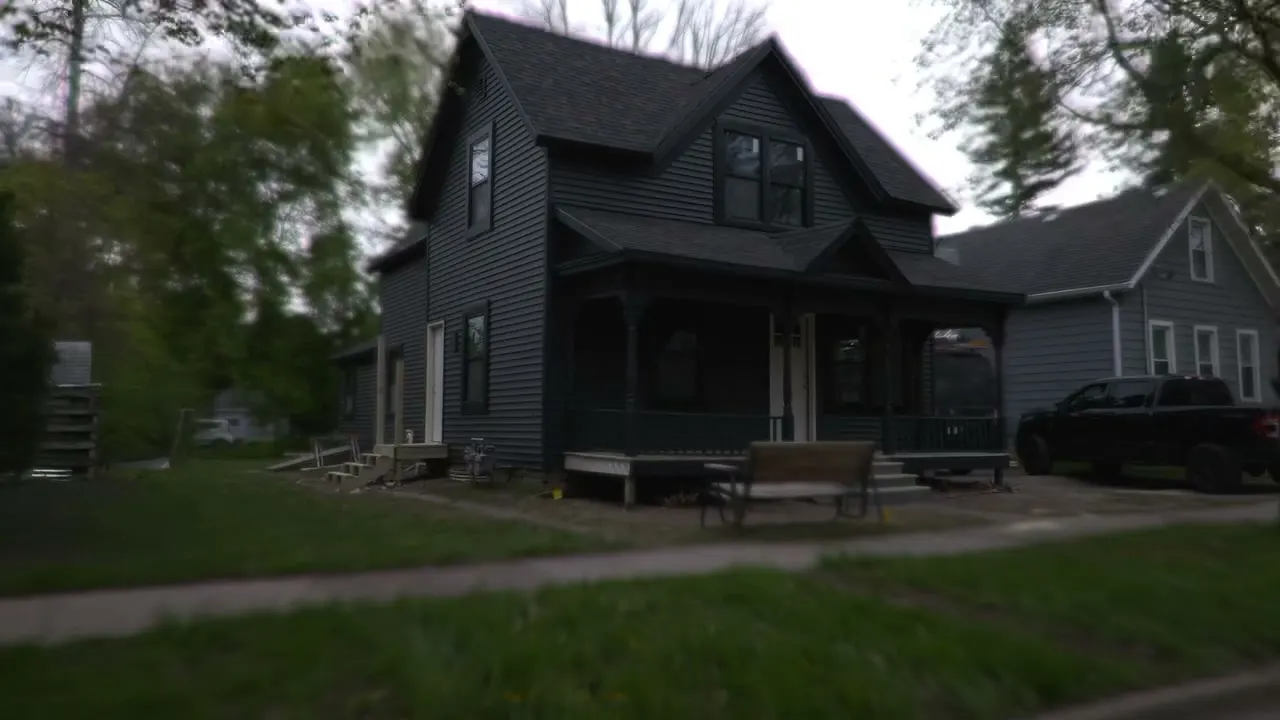 After: the same Victorian restored in dark lap siding with black trim and a black porch
