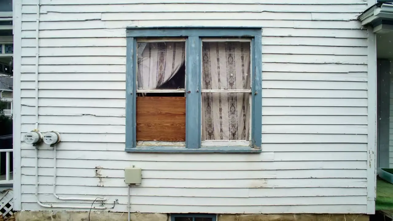 Before: a boarded-up window in worn white siding