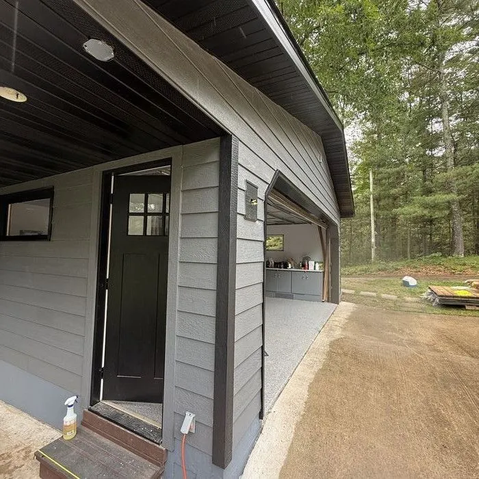 New dark lap siding and black trim around a side door and soffit light