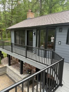 New grey siding and a black-railed deck wrapping the back of the house