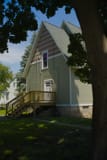 A sage-green gable house with new wooden entry stairs