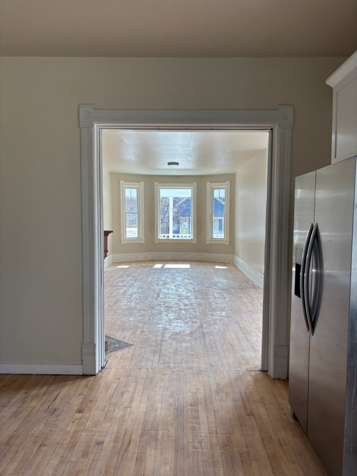 A Del's interior: a trimmed doorway opening onto a bright bay-window room with hardwood floors