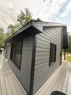 Grey siding with black corner trim and window frames on the finished addition