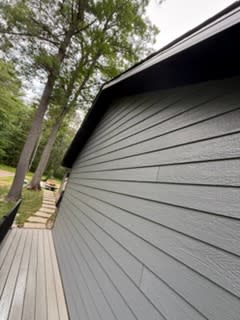 Long run of new grey lap siding under black fascia beside the deck