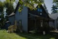 A blue-grey Victorian house with a front porch