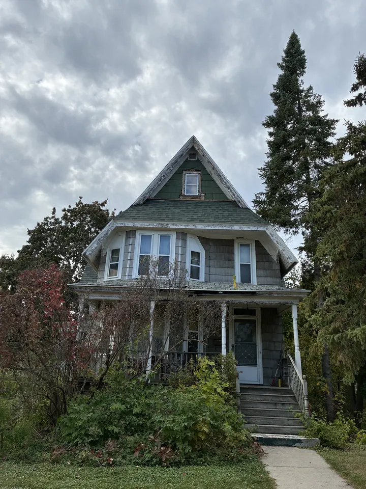 Before: the house at 503 Michigan with worn gray siding under an overcast sky