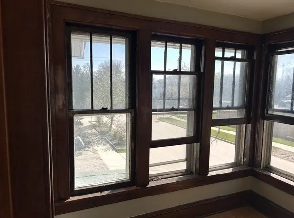 Before: old dark-stained wood windows in the corner of a room