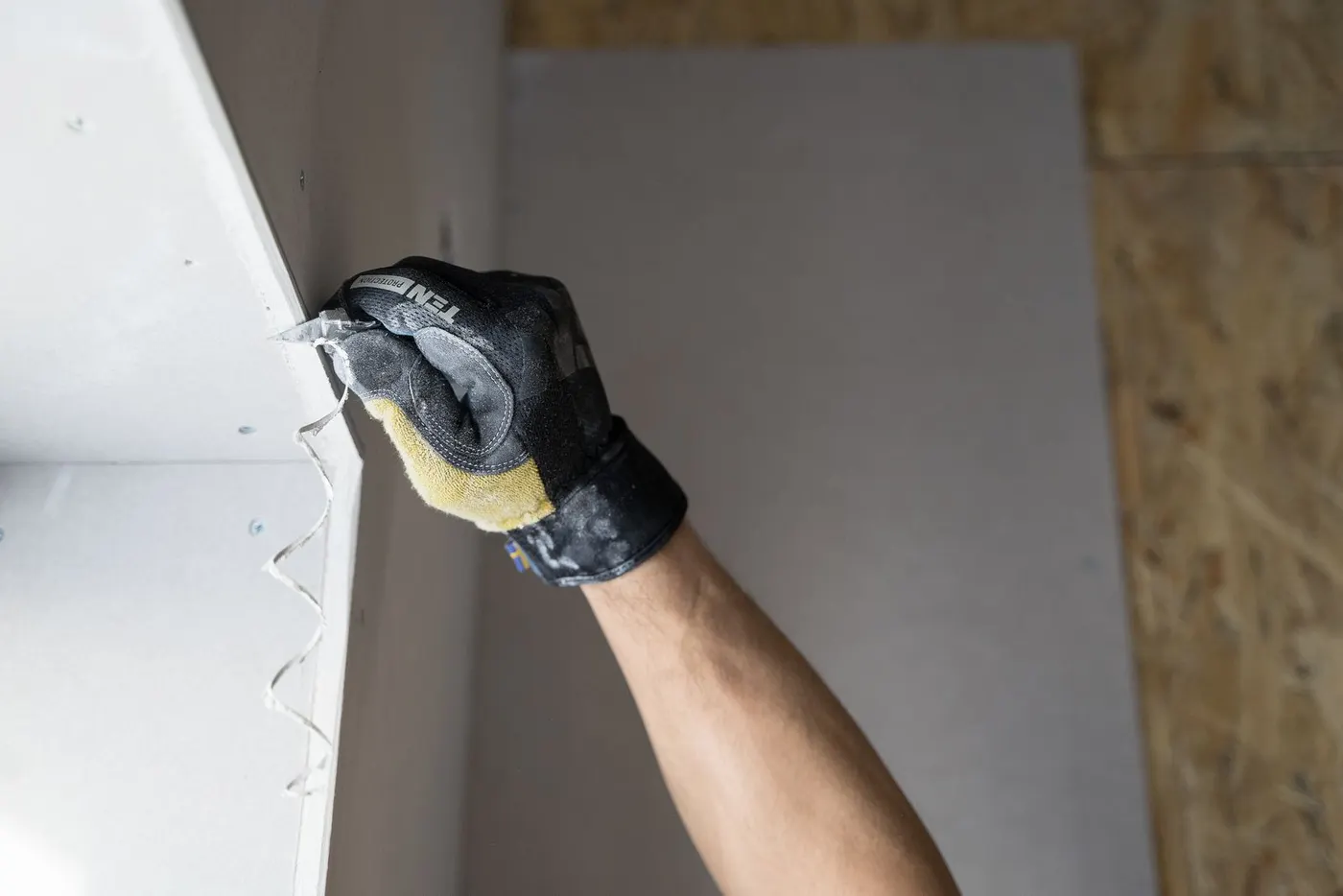 Gloved hand finishing a new drywall panel (representative photo)