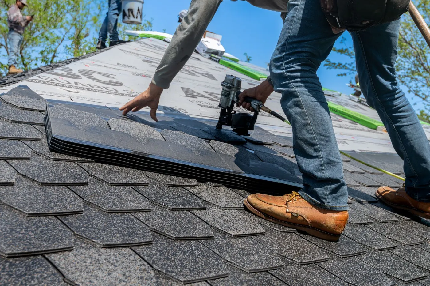 Roofer nailing new architectural shingles (representative photo)